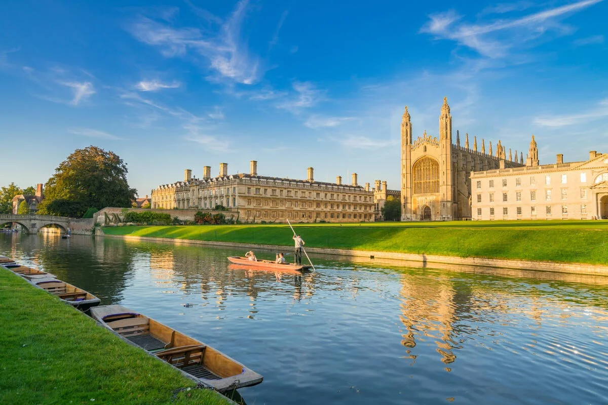 イギリスの大学都市ケンブリッジを流れるケム川の美しい風景。キングス・カレッジ礼拝堂などの歴史的建造物が水面に映り、パント船が浮かぶ穏やかな一日が描かれている。