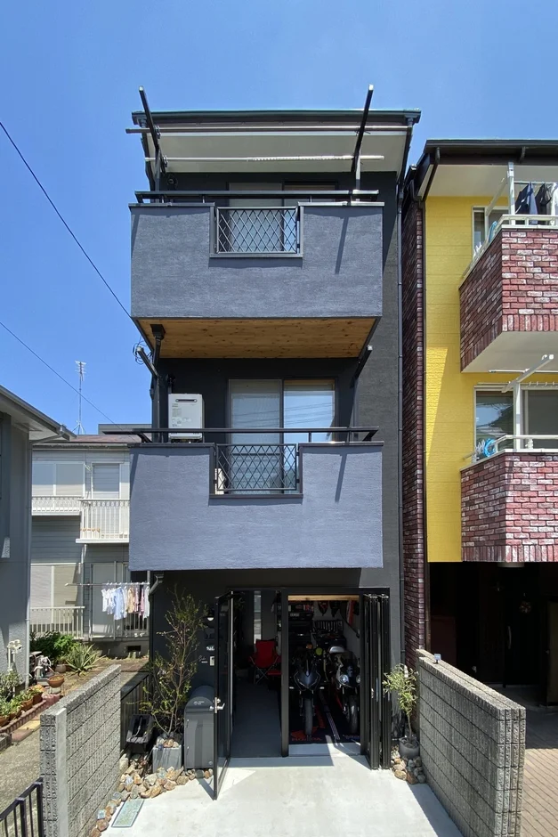 ダークグレーの外壁が特徴的な3階建てのモダンな住宅