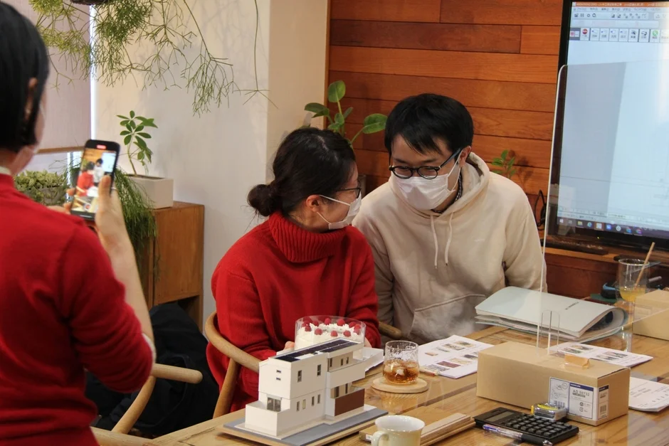 建築模型を囲んで打ち合わせをする男女