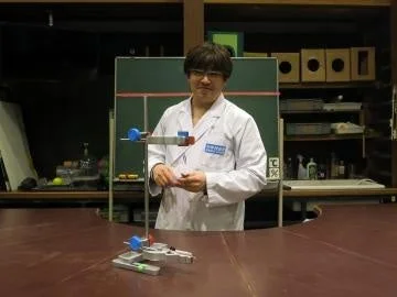 白衣を着た男性が実験器具の前に立つ様子