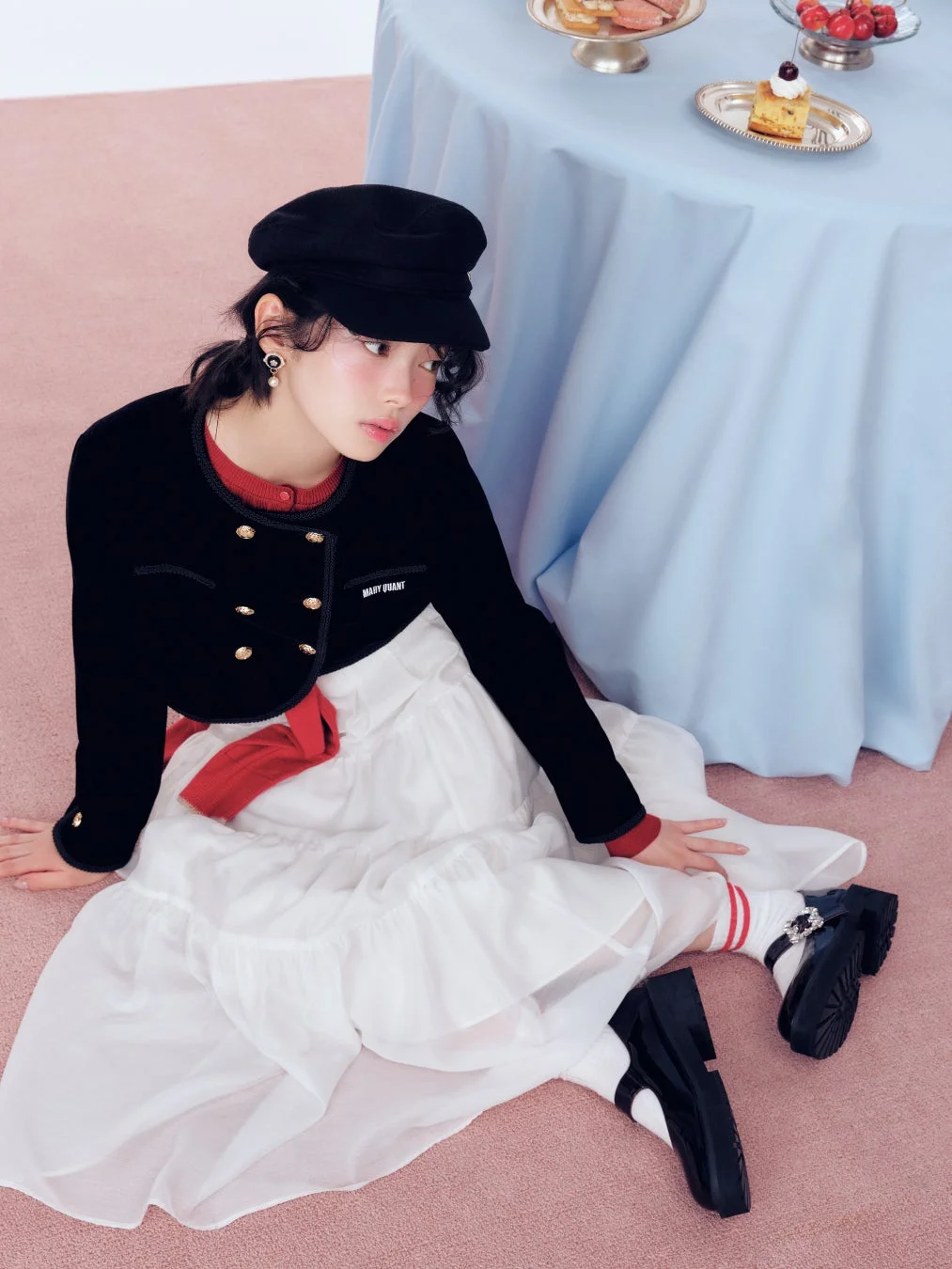 ピンクの床に座る女性のファッション