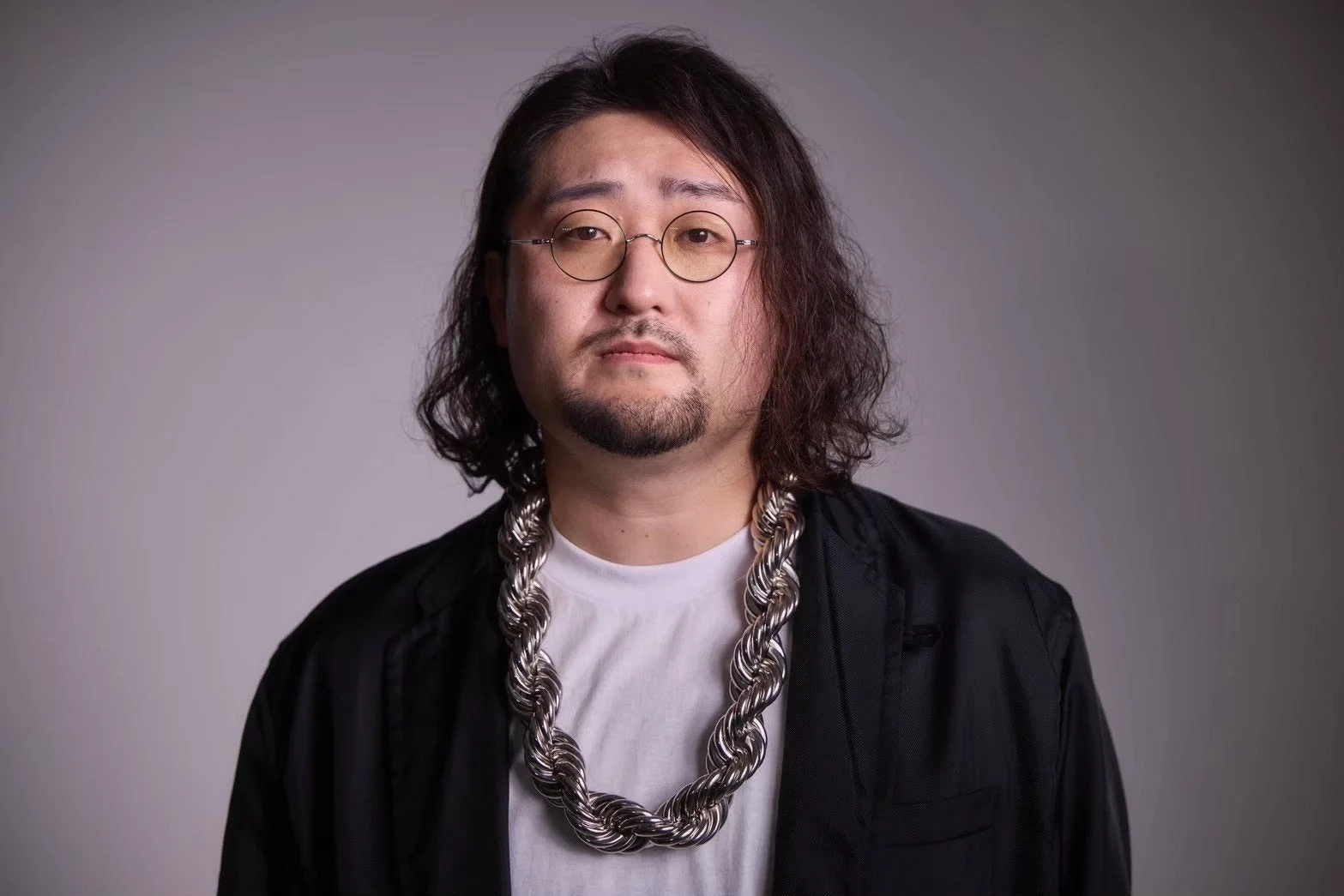 長髪とひげ、丸眼鏡をかけた男性のポートレート