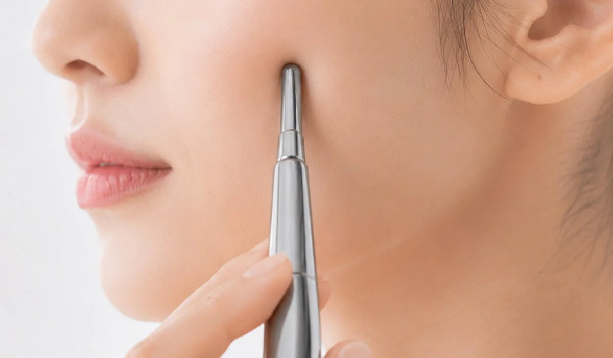 女性が顔の頬に細身の美顔器を使用しているクローズアップ画像