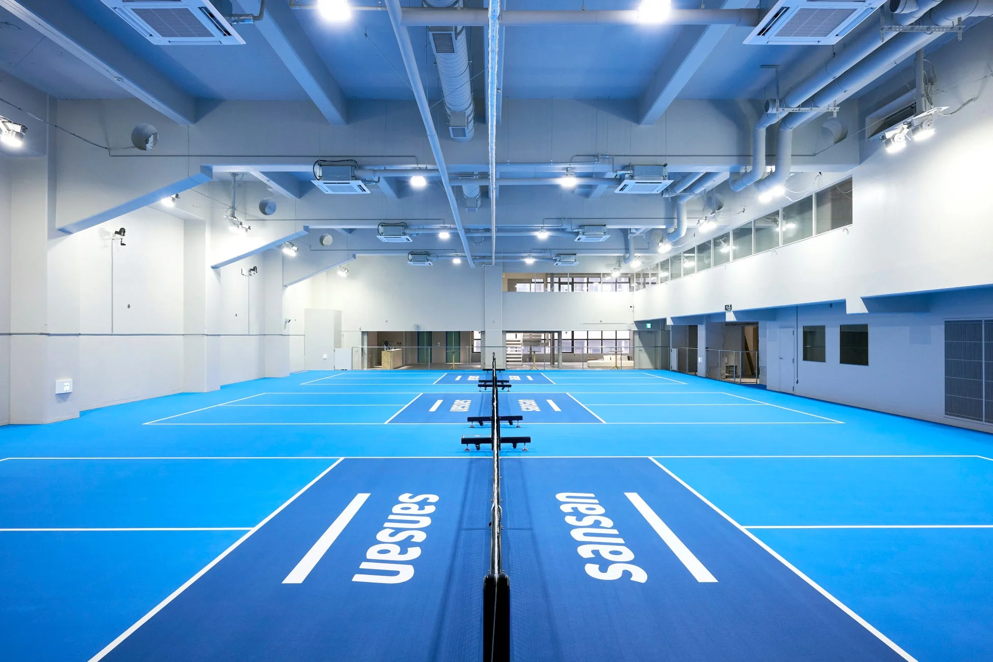 青い床に白いラインが引かれた屋内スポーツコートの全景