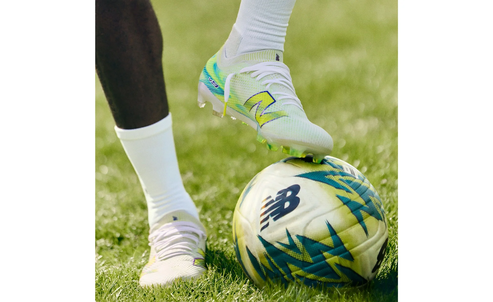 選手がボールに足を置くニューバランスのサッカースパイク