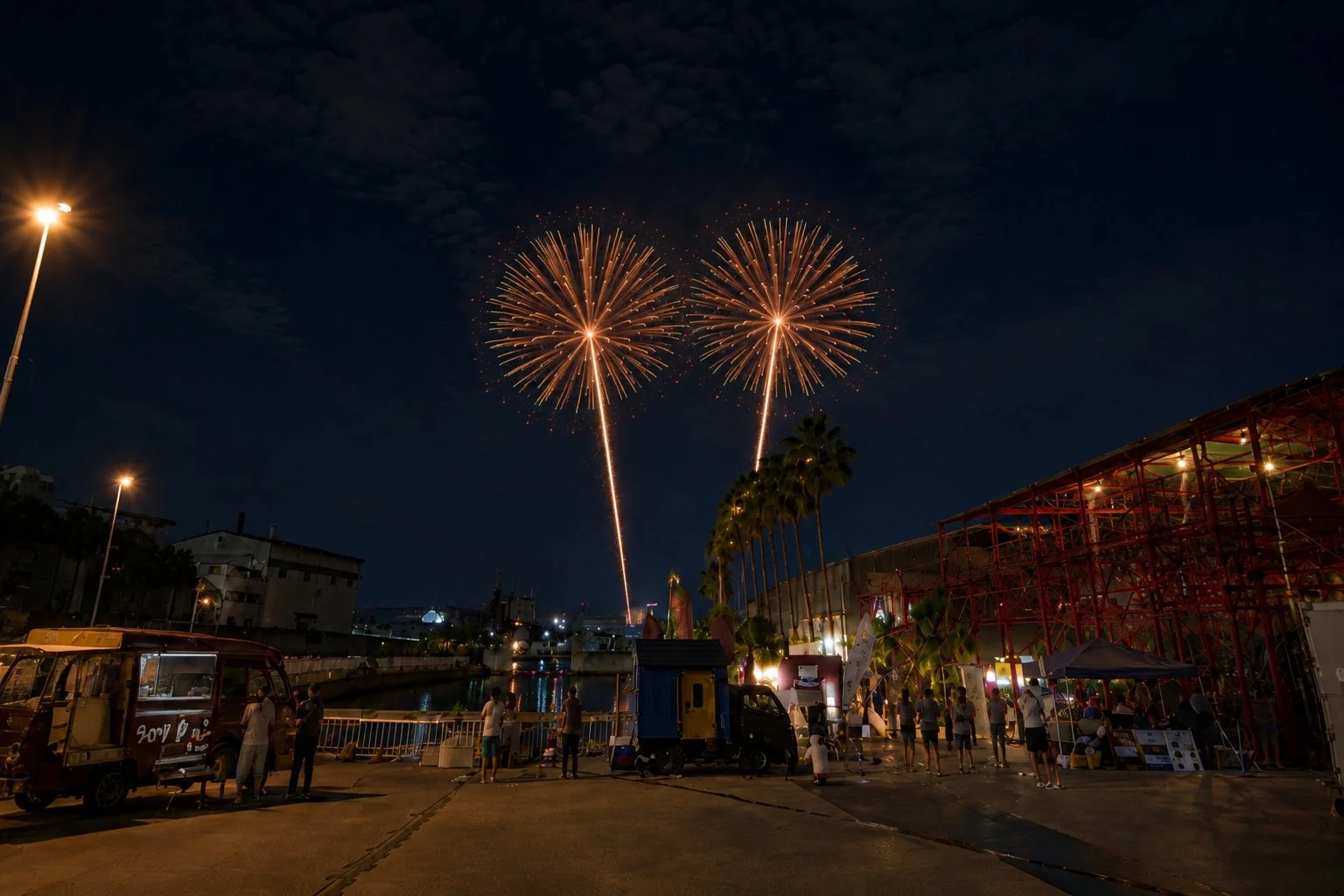 夜空に打ち上げられる花火と水辺のイベント会場