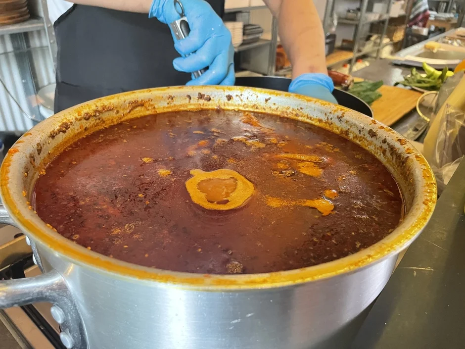 厨房で煮込み料理をかき混ぜる料理人