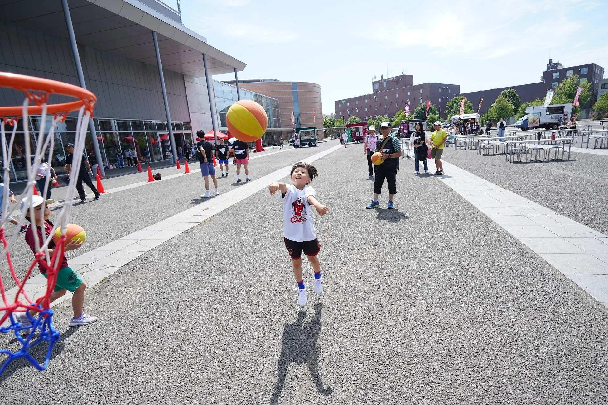 屋外イベントでミニリングでバスケットボールを楽しむ子供たち