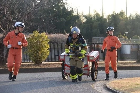 訓練中に機材を運んで走る消防士