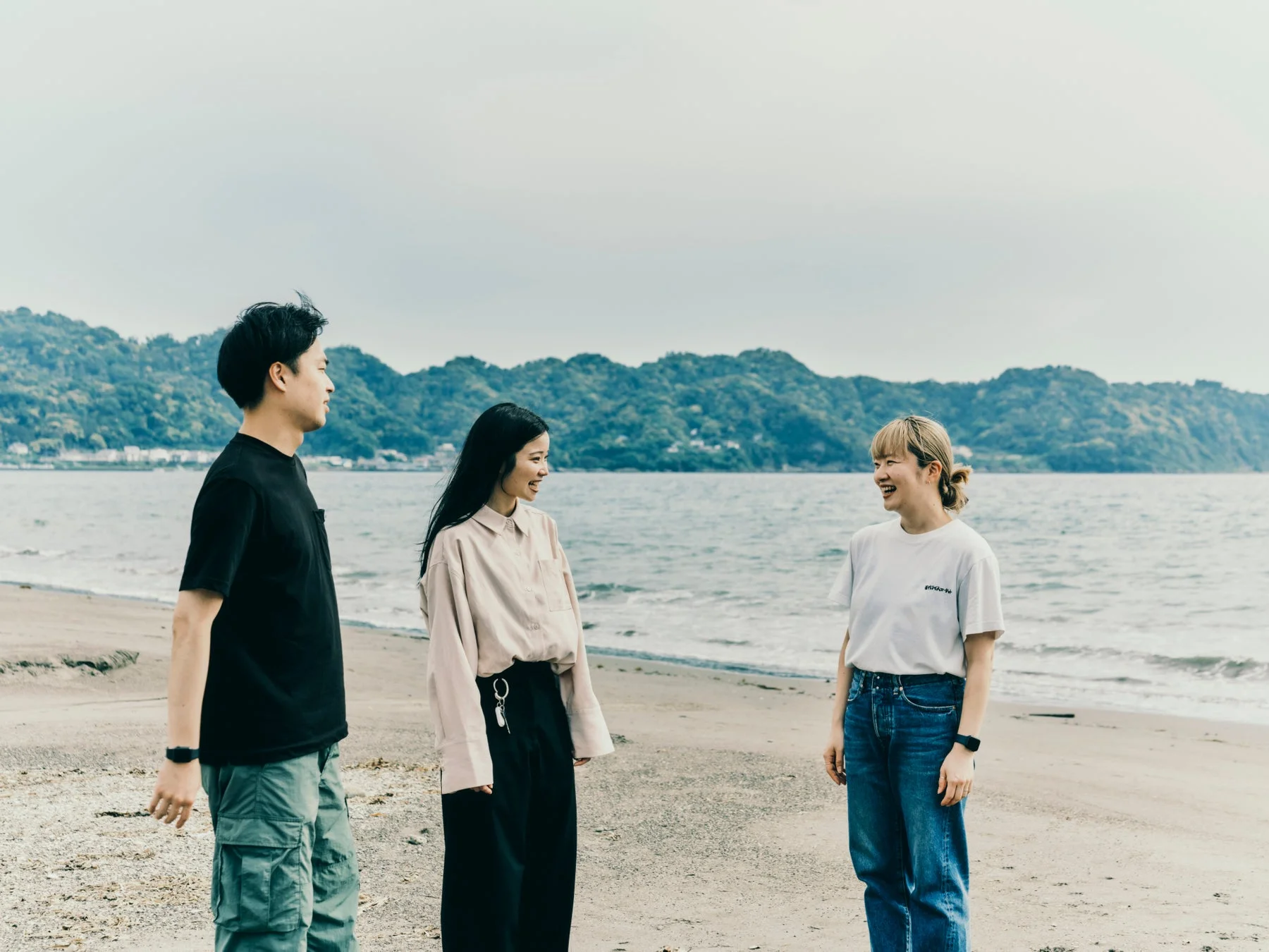 砂浜で笑顔で会話を楽しむ3人の若者