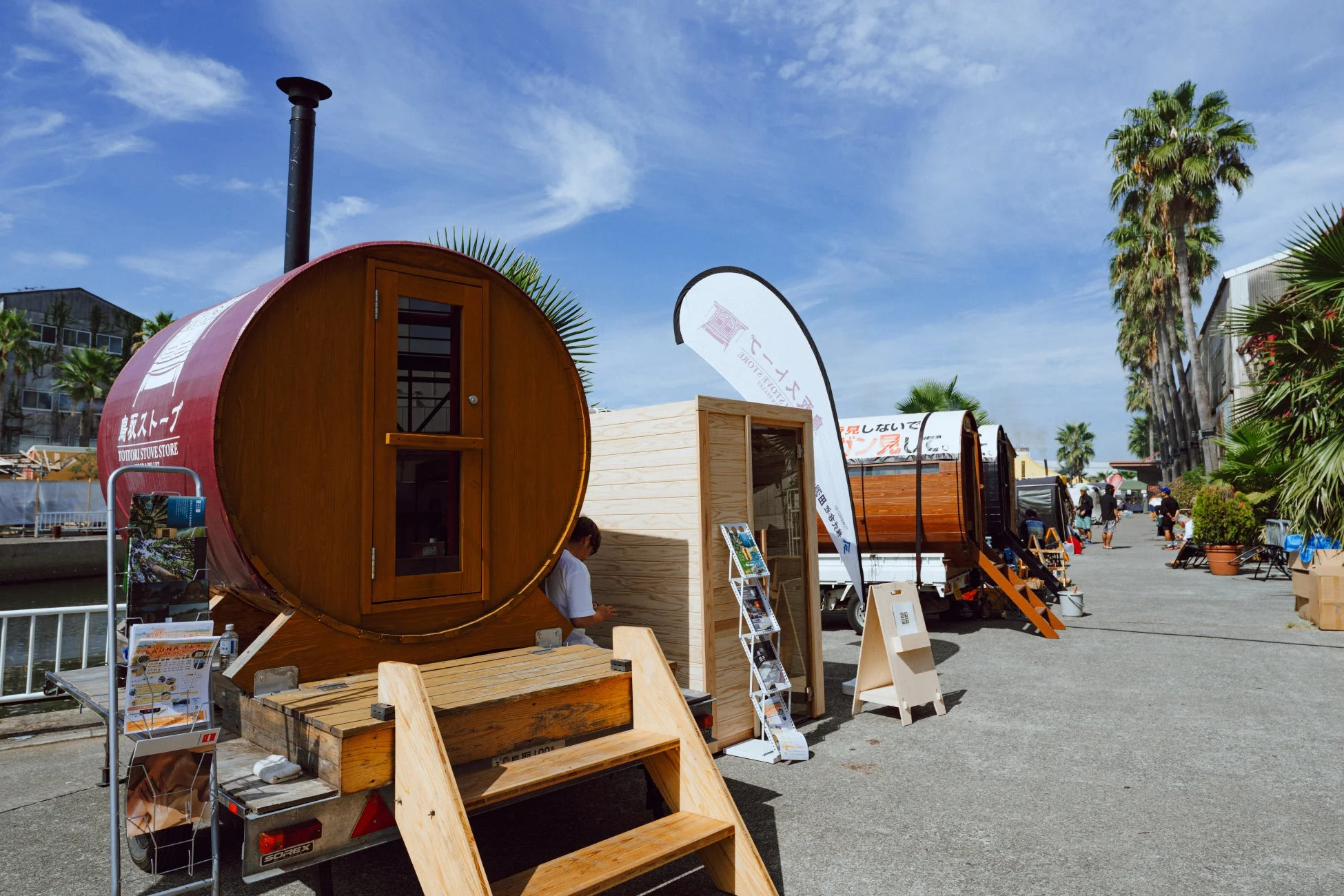 屋外イベント会場に展示されたバレルサウナと木製小屋