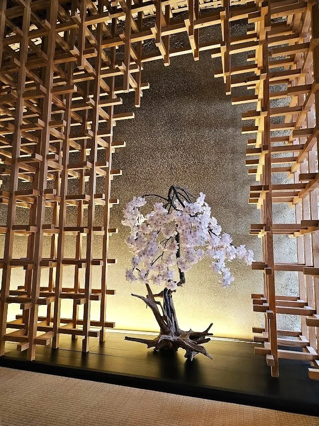 木組みの格子に囲まれた和モダンな空間に、白い桜のオブジェが飾られています。金色の壁が温かく照らされ、静かで美しい日本の美意識を感じさせるインテリアです。