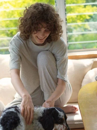 女性が犬とソファでリラックスしている画像
