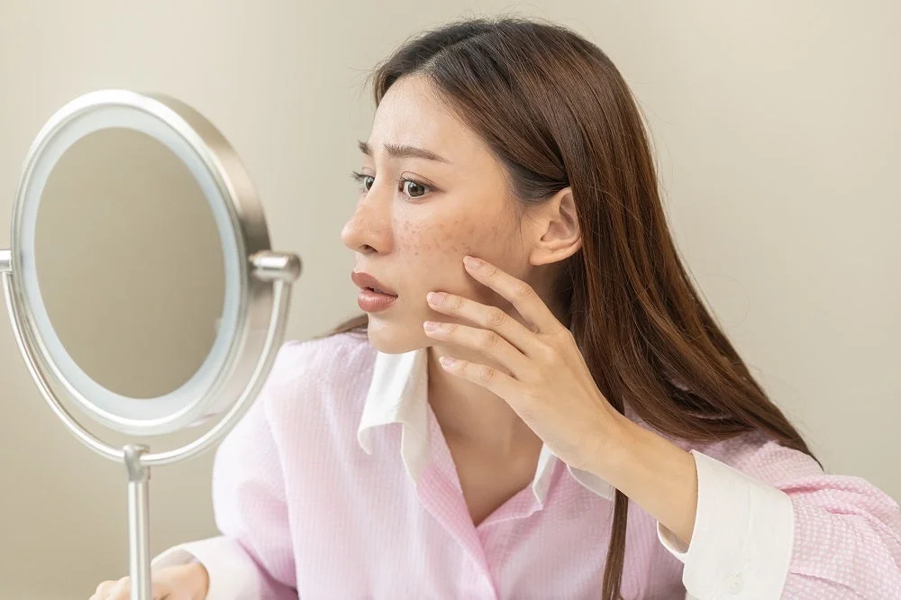 鏡で肌の悩みをチェックする女性