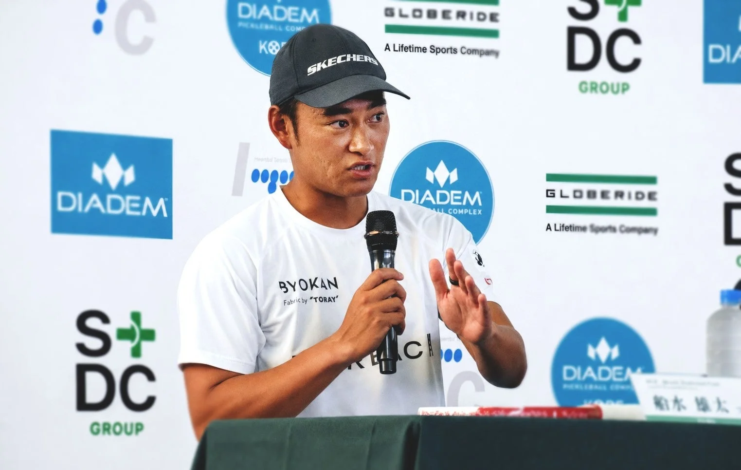 黒いキャップをかぶった男性がマイクを持って話している様子。背景にはDIADEM、GLOBERIDE、S+DC GROUPなどの企業ロゴが見られ、船水雄太氏が記者会見のようなイベントでスピーチを行っている場面です。