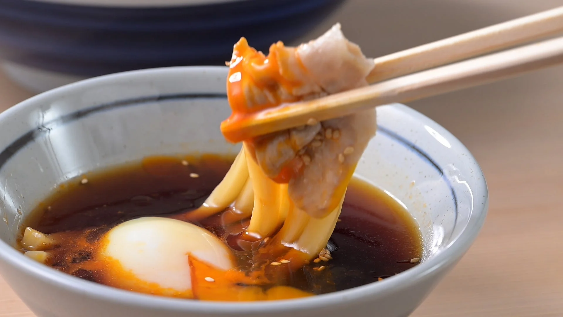 温泉玉子入りのつけ汁に麺を浸す様子
