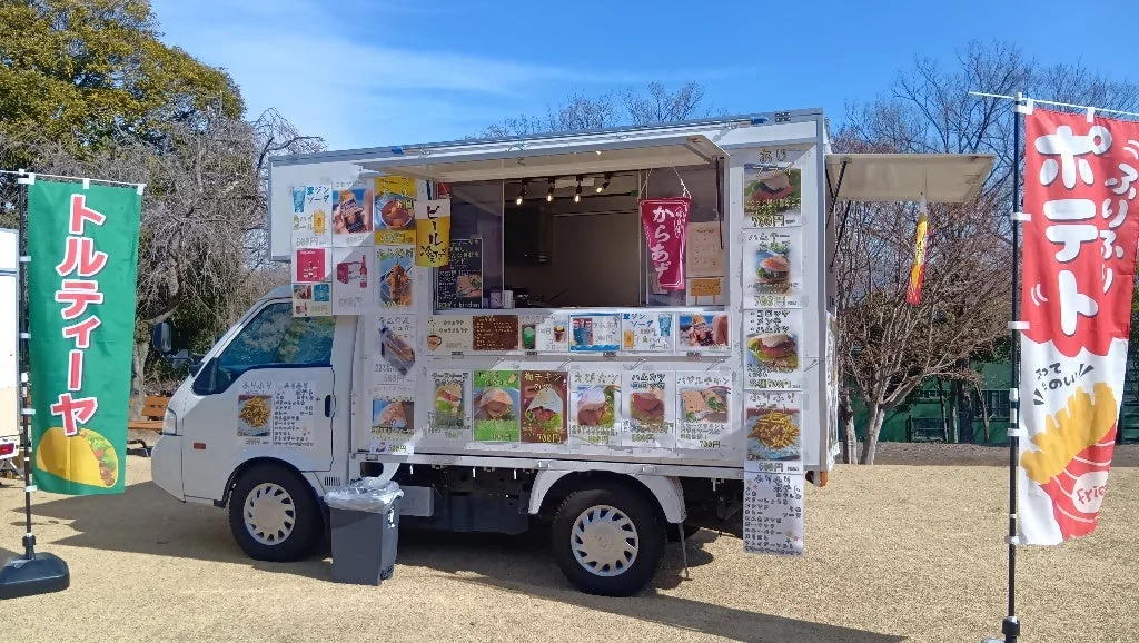 青空の下、公園のような場所に停車している白いフードトラック