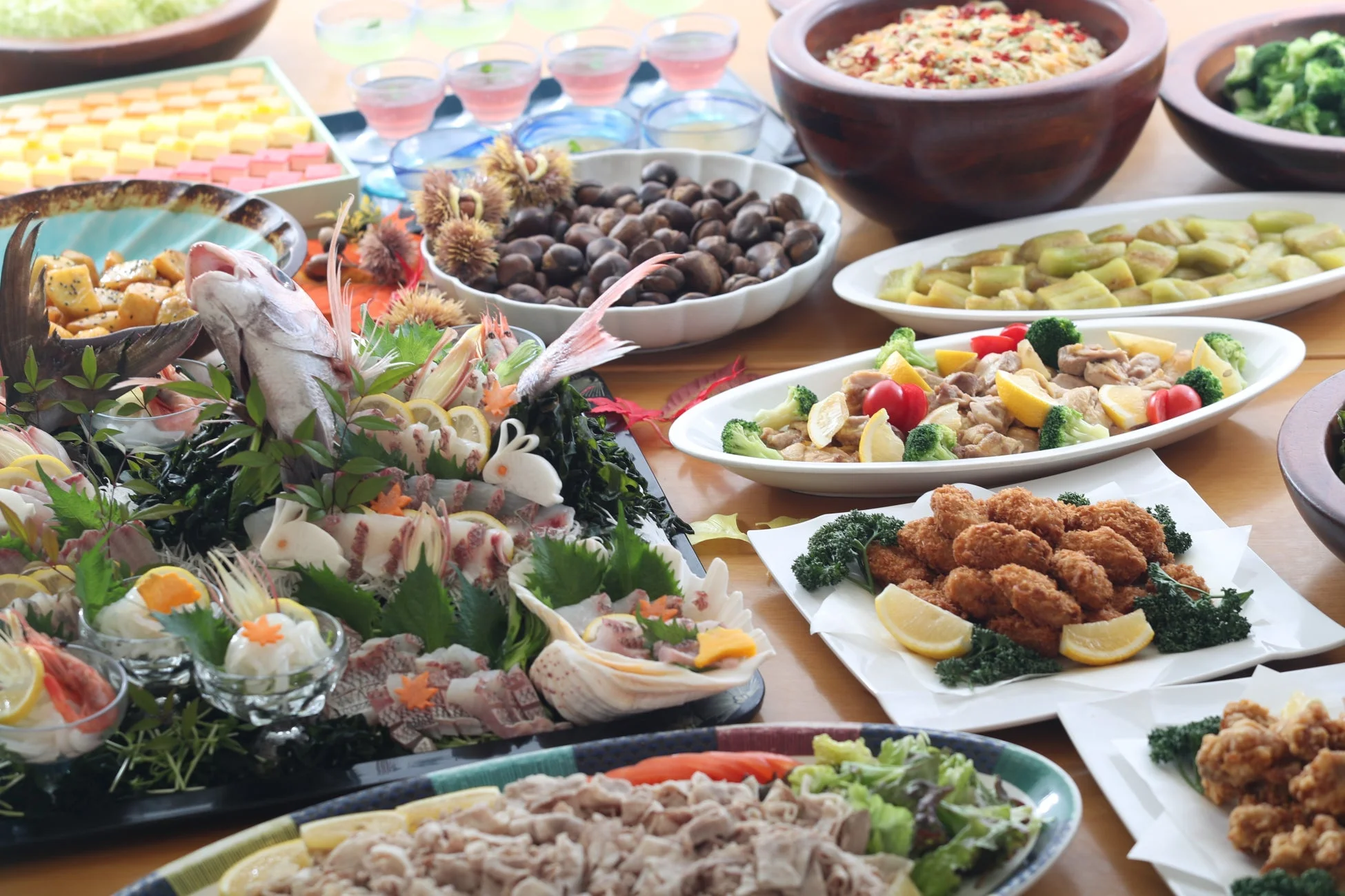 豪華な和食のビュッフェスタイルの食卓が写っています。刺身の盛り合わせ、揚げ物、栗、様々な副菜やデザートが並び、彩り豊かで食欲をそそる光景です。