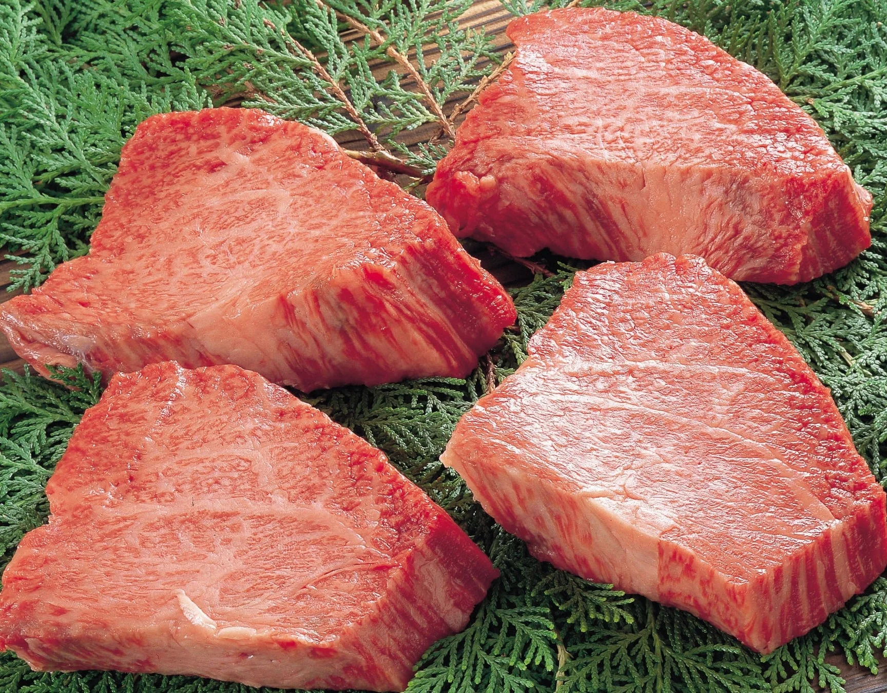 緑の葉の上に置かれた4枚の新鮮な生肉の塊