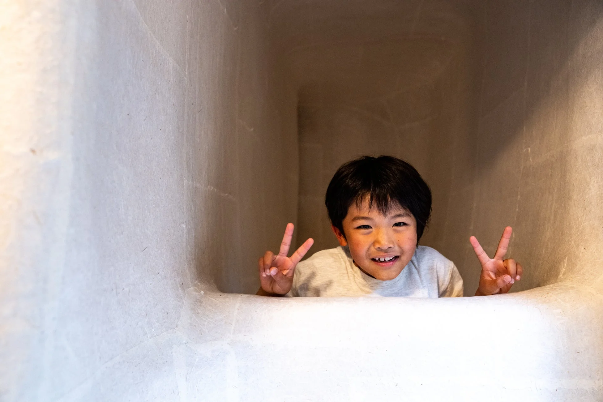 白いトンネルから顔を出す子供