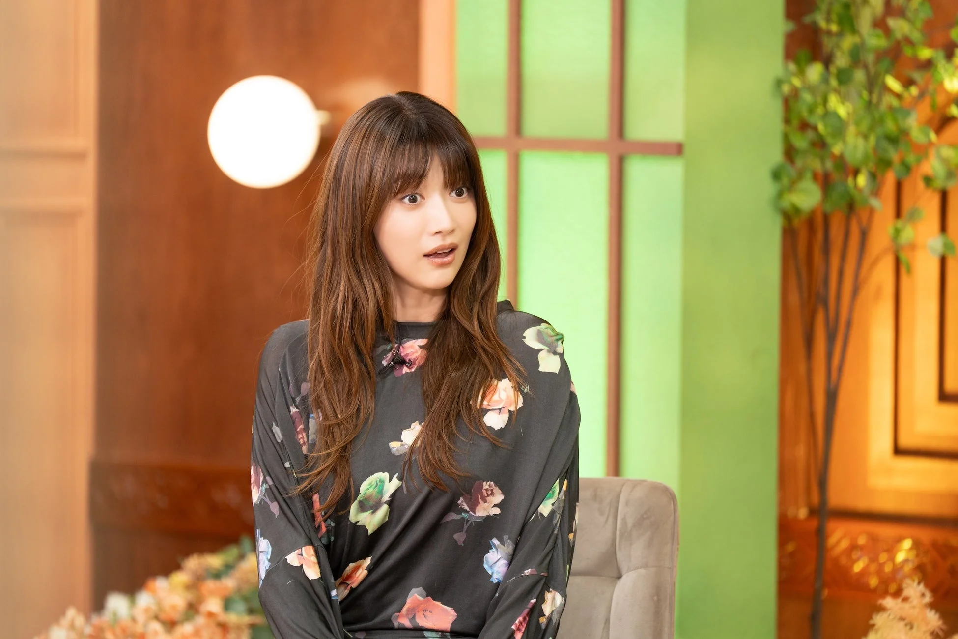 花柄のトップスを着て驚いたような表情の若い女性