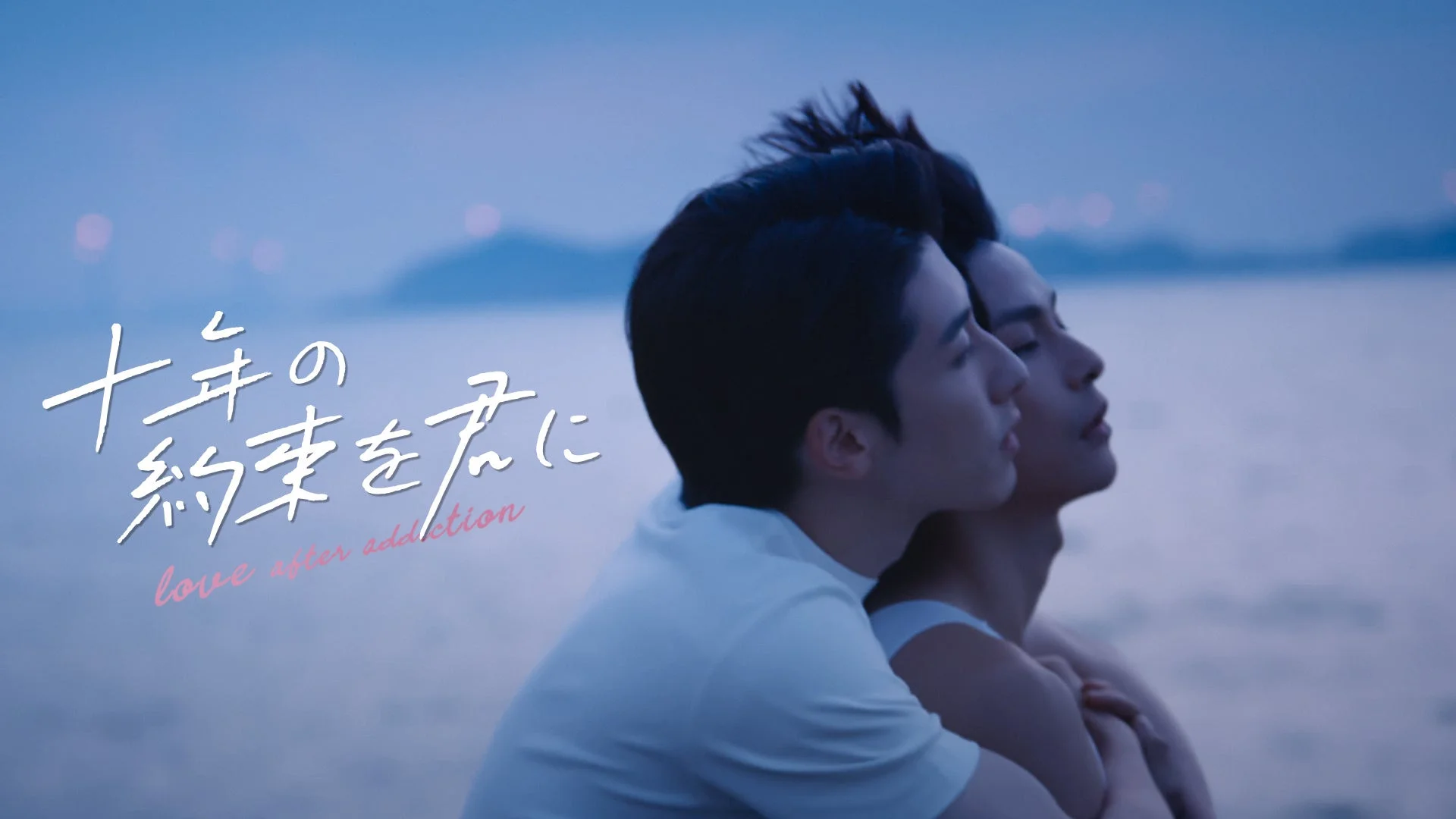夕暮れ時の水辺で抱き合う二人の男性