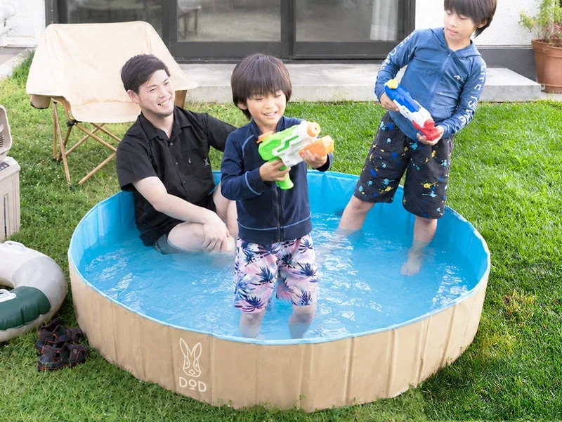 庭の簡易プールで水遊びを楽しむ親子