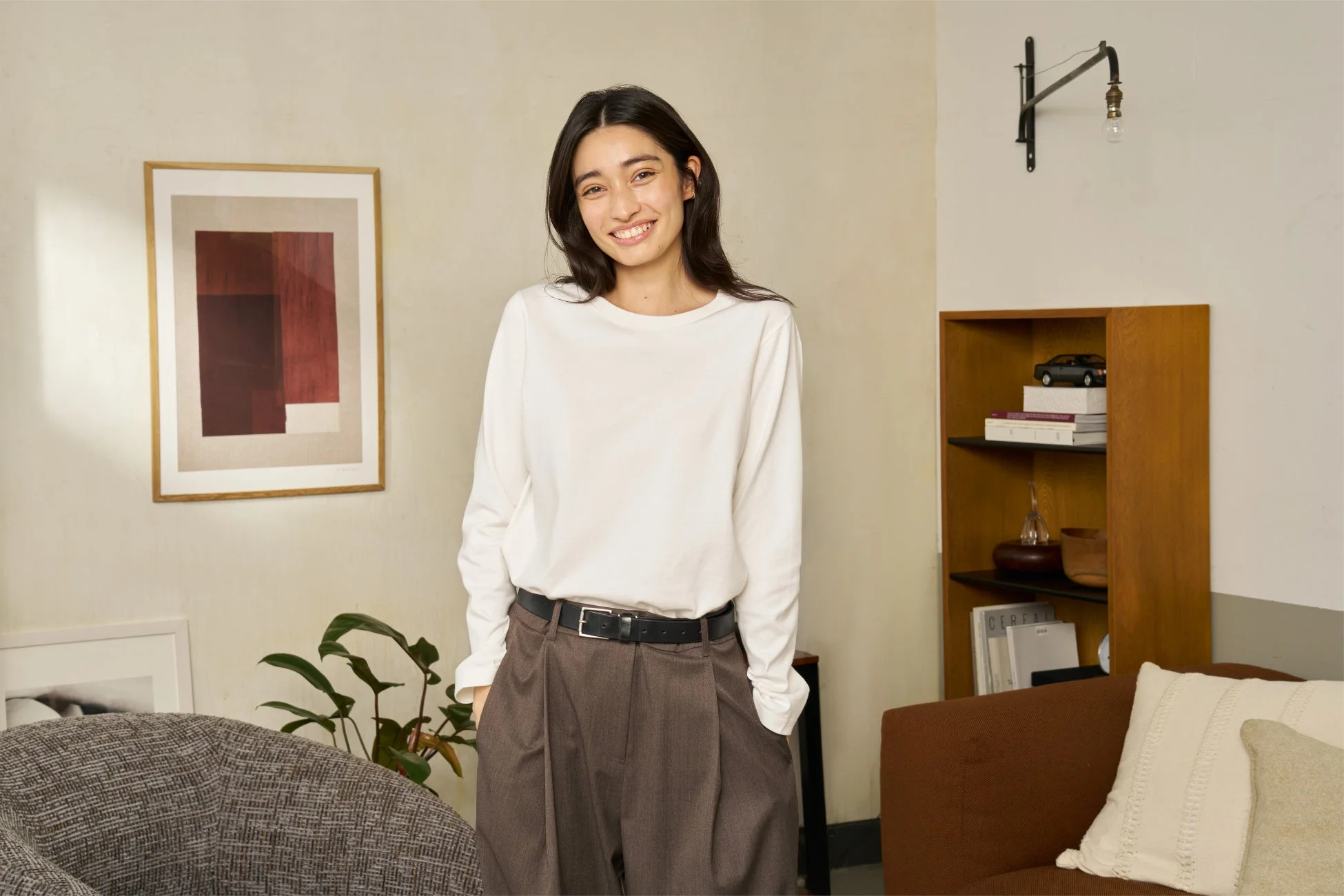 白い長袖Tシャツとブラウンのワイドパンツを着用した女性