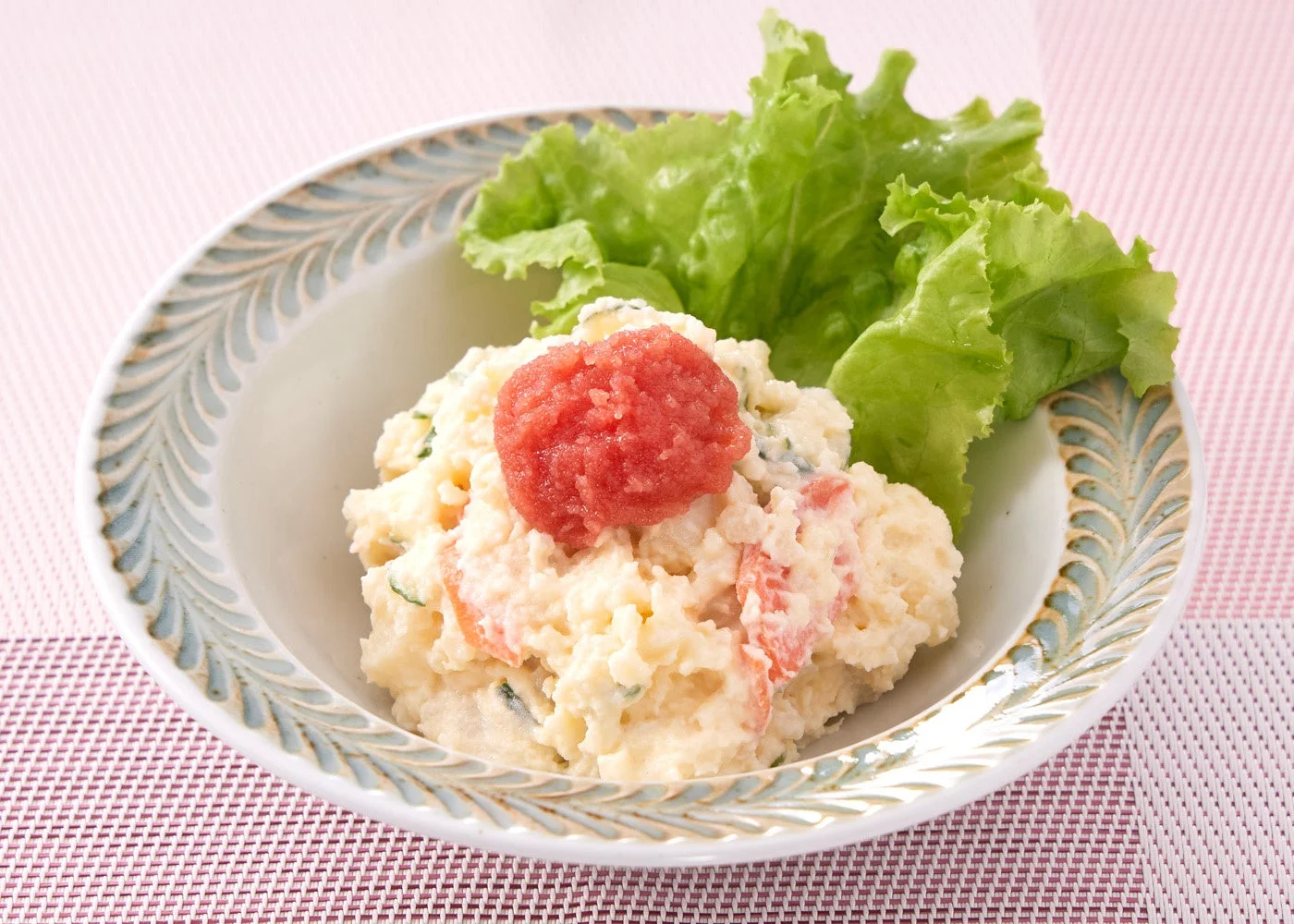 明太子がのったポテトサラダが白い器に盛り付けられており、付け合わせのレタスが添えられています。
