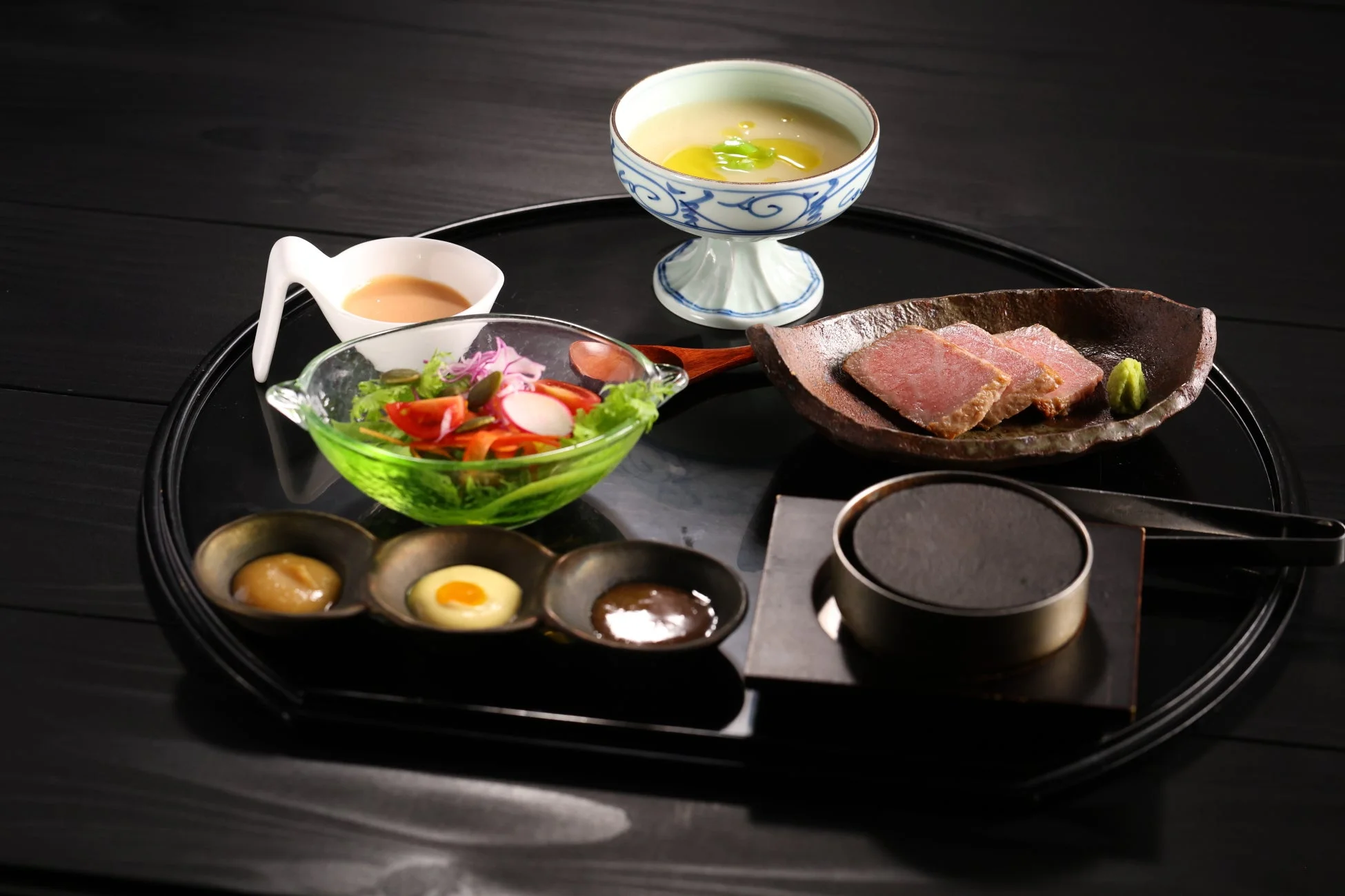 黒いお盆に盛り付けられた和風コース料理