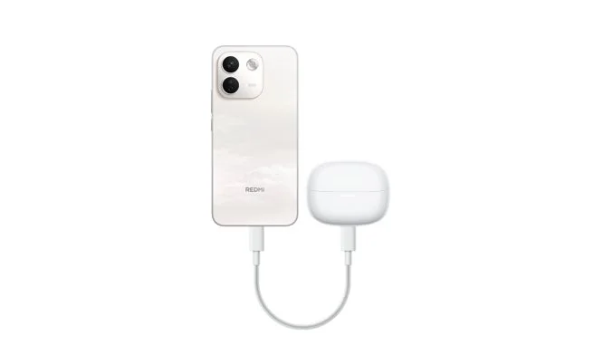 白いスマートフォン「Redmi」が白いワイヤレスイヤホンの充電ケースをケーブルで給電している様子