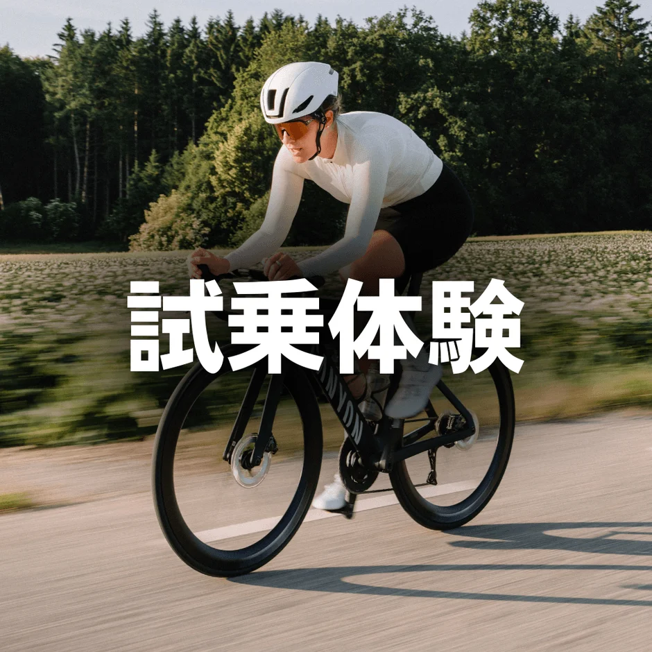 白いヘルメットとサングラスを着用した人がロードバイクに乗って舗装された道を走行