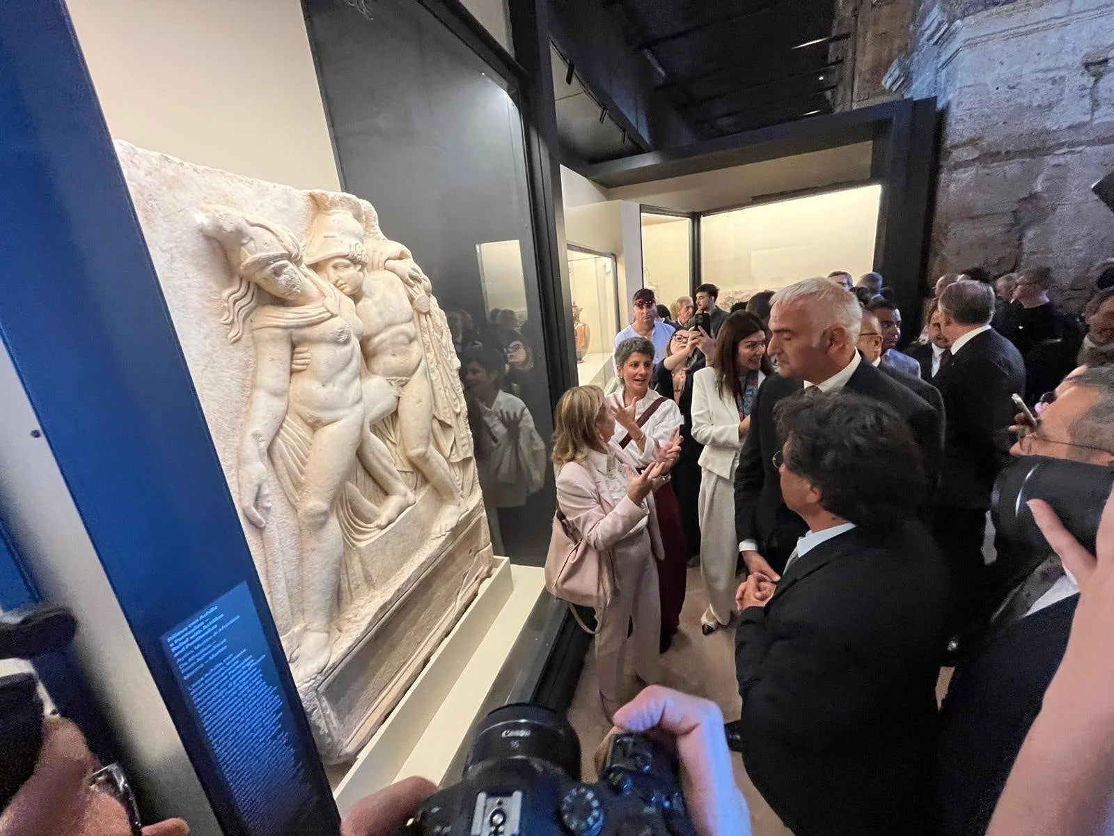 美術館で古代のレリーフ彫刻を鑑賞する人々