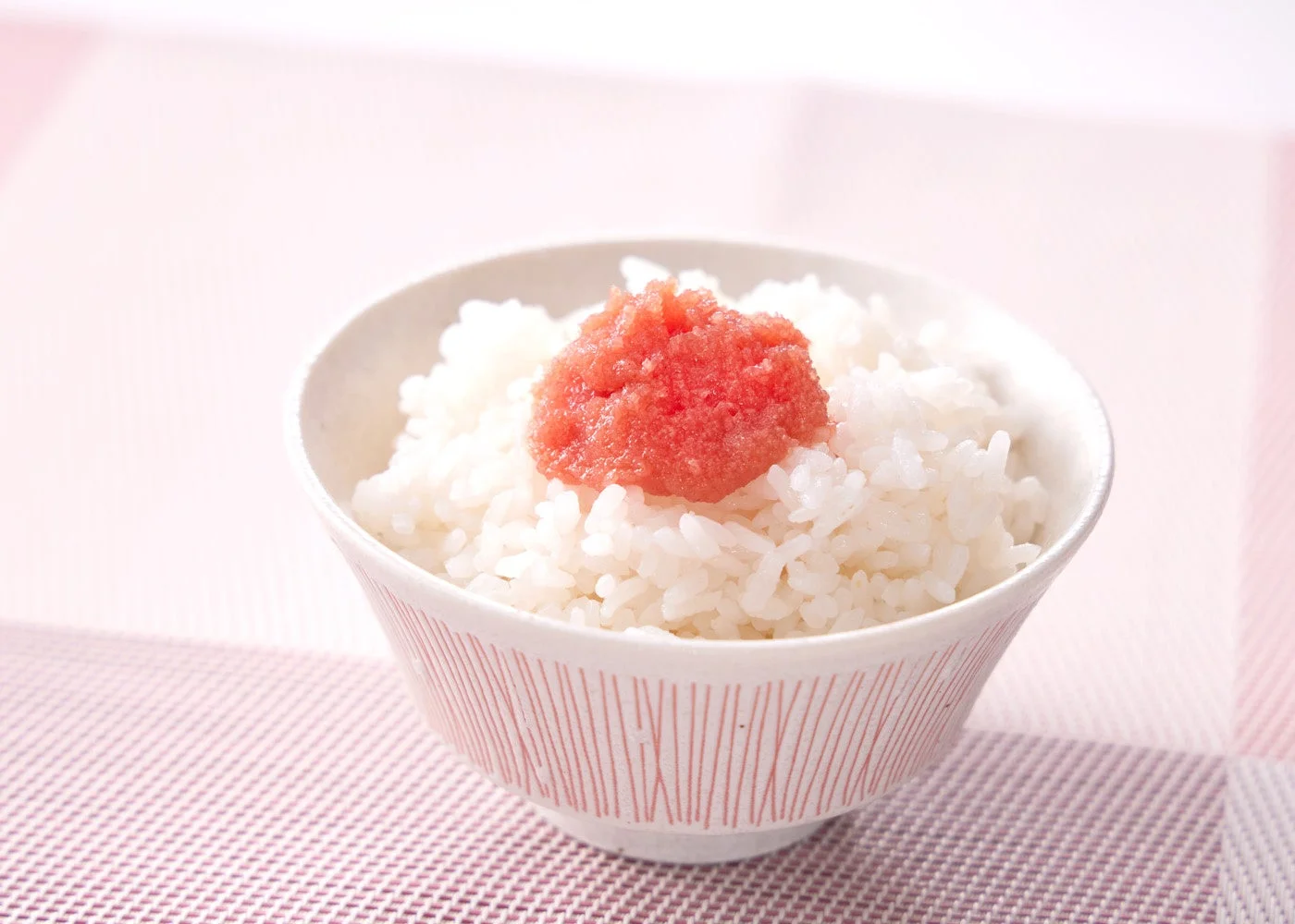 白いご飯の上に鮮やかな赤色の明太子がのったシンプルな和食の一品です。