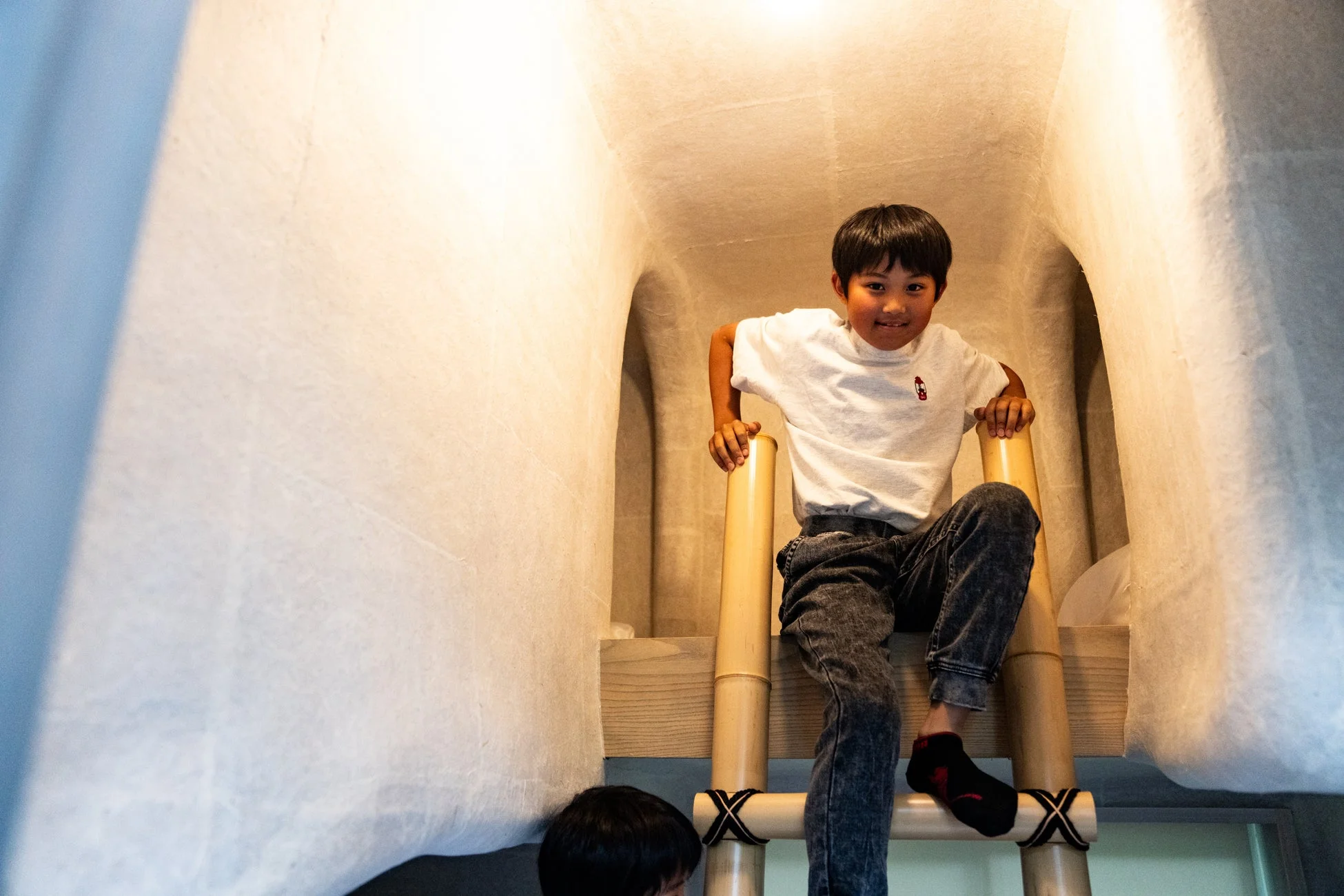 竹製のはしごを登る少年