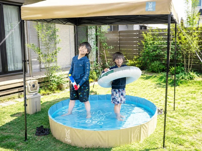 日よけのテントの下でプールを楽しむ男の子たち