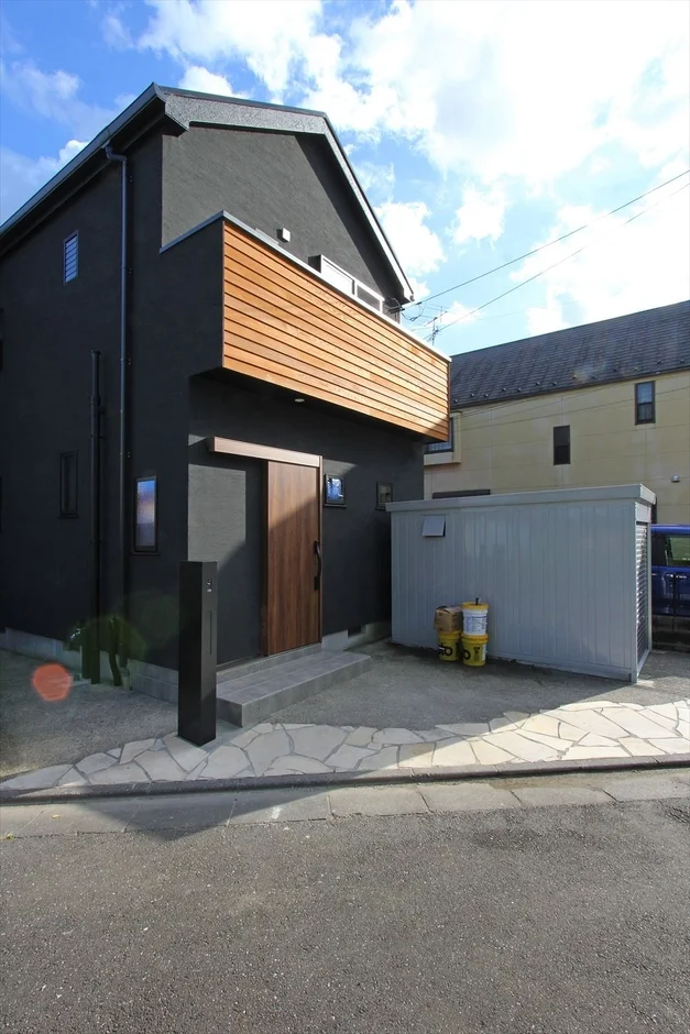 黒い外壁と木目調バルコニーの住宅外観