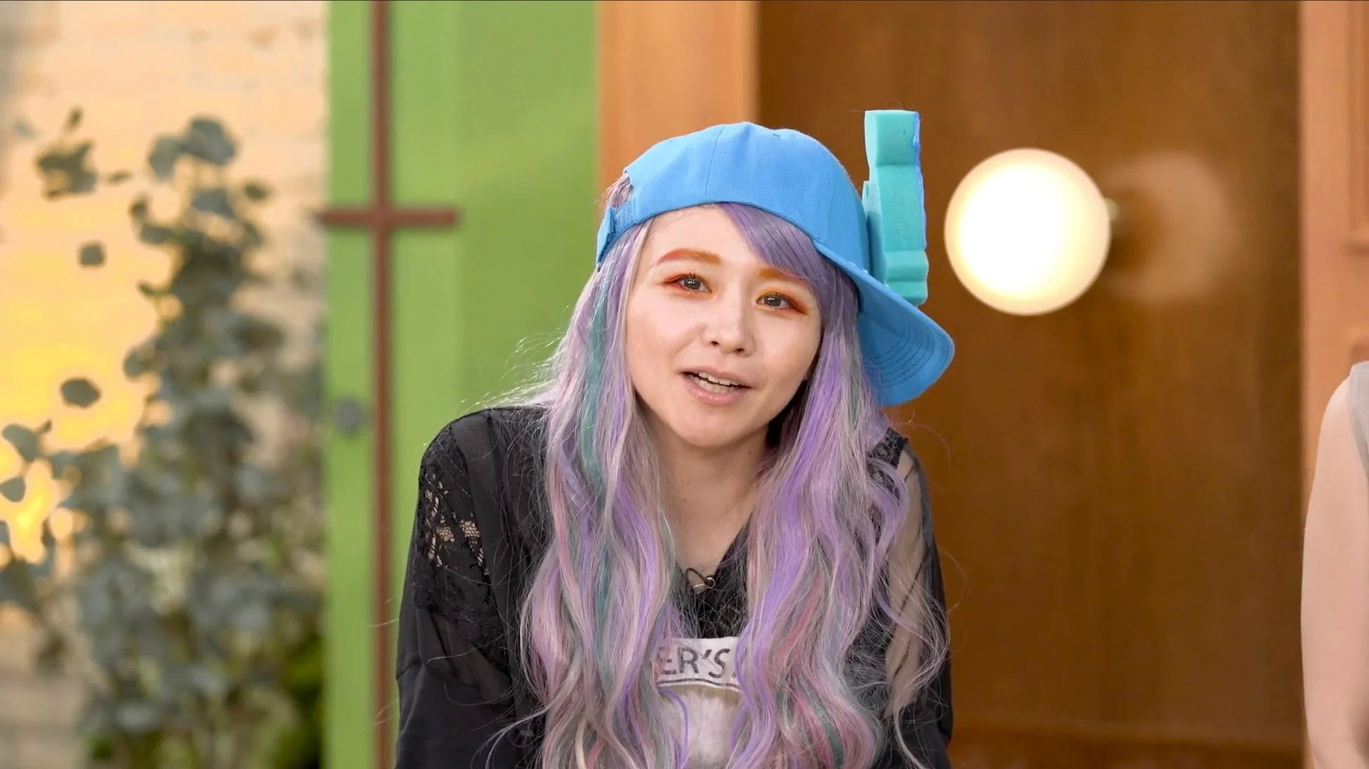 カラフルなロングヘアと個性的なオレンジのアイメイクが特徴の女性