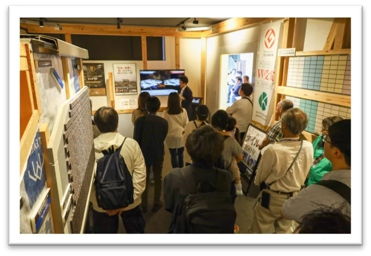 展示会でタイルや建築関連の展示を見学する人々
