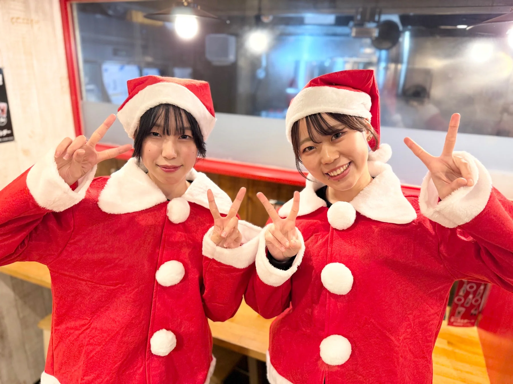 サンタクロースの衣装を着た2人の女性が笑顔でピースサイン