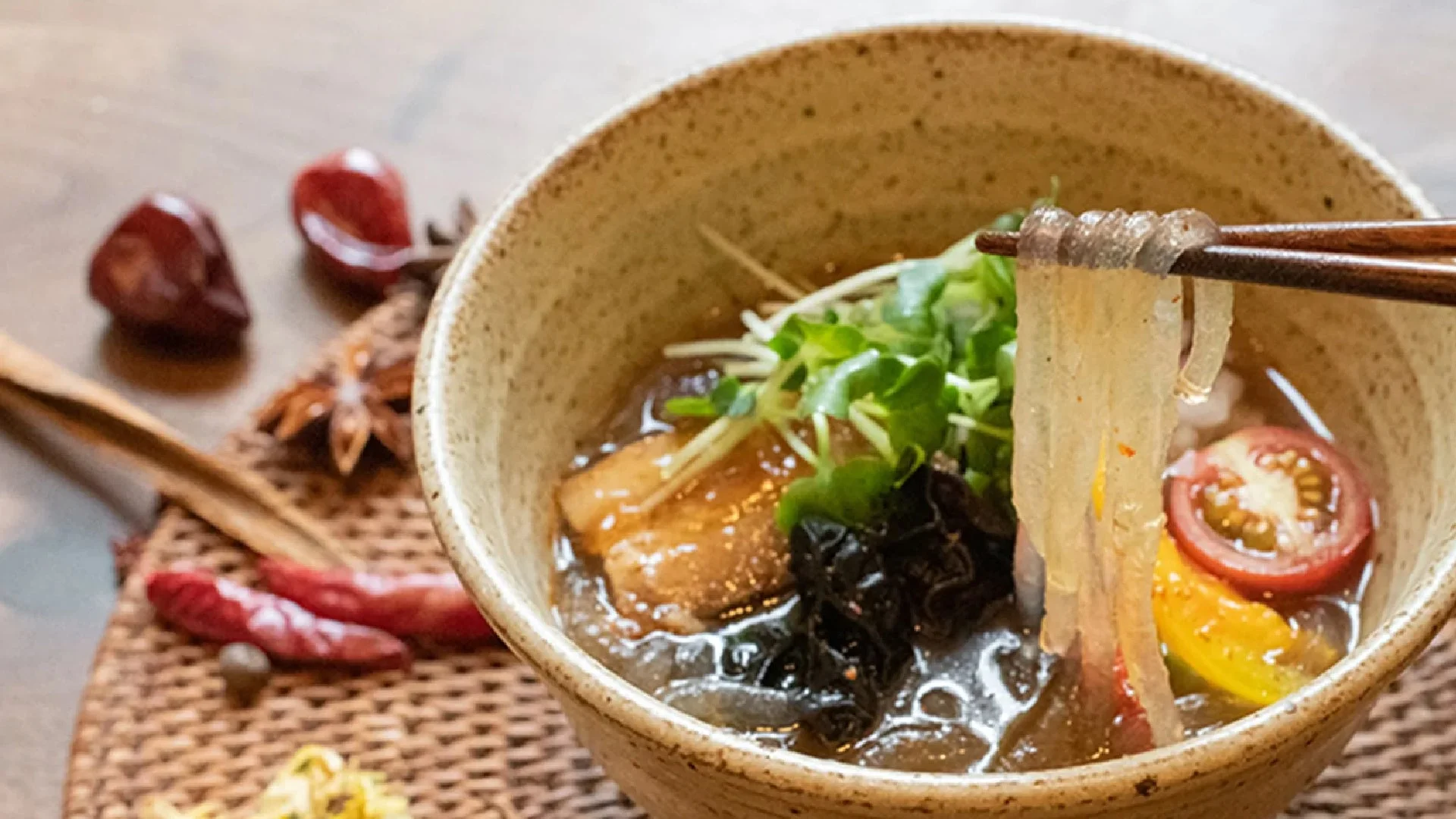 箸で持ち上げられた透明な麺と具材
