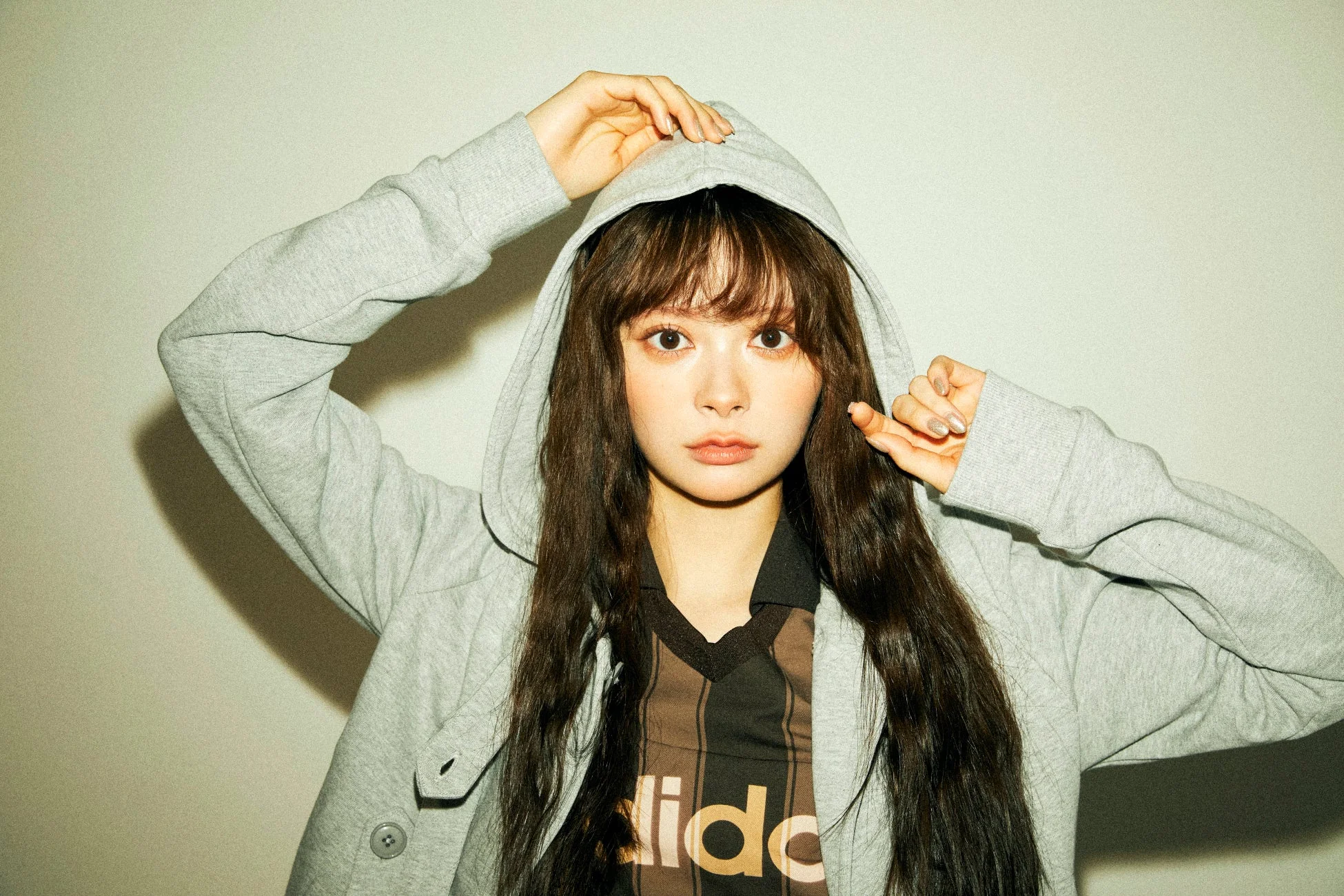 灰色のパーカーとアディダスのTシャツを着た女性