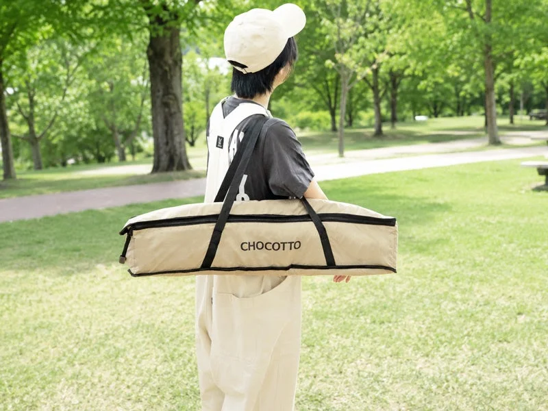 CHOCOTTOの収納バッグを肩にかけ公園を歩く人物