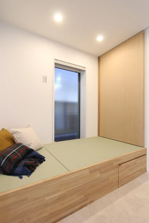 和モダンな雰囲気の部屋で、木製の小上がりに畳が敷かれ、収納付きの機能的なデザイン