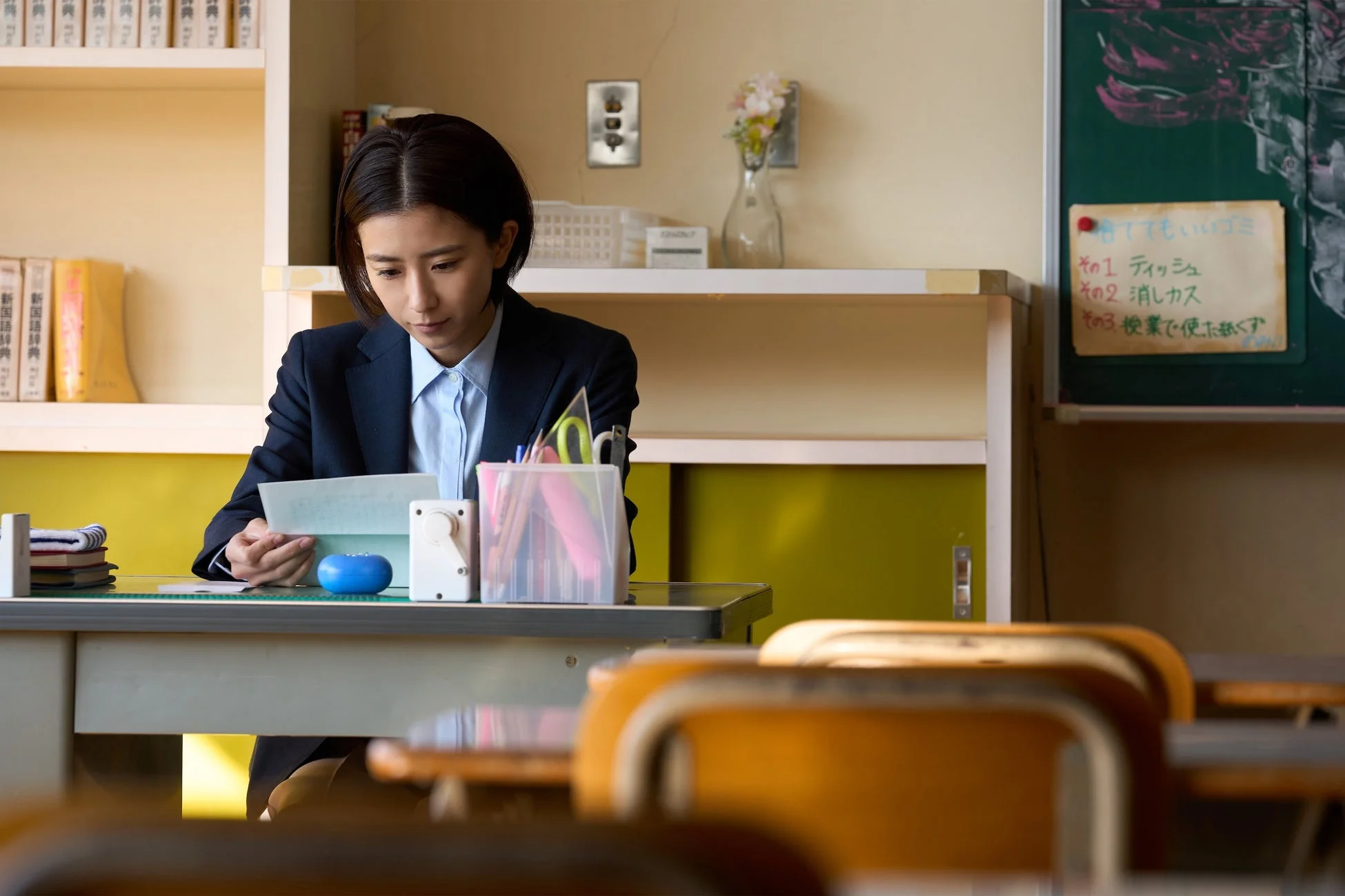 教室の机で書類を読む女性教師