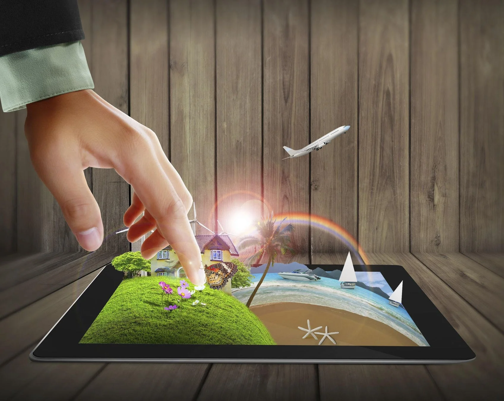 手がタブレットを操作し、画面から家や風景が飛び出している合成画像