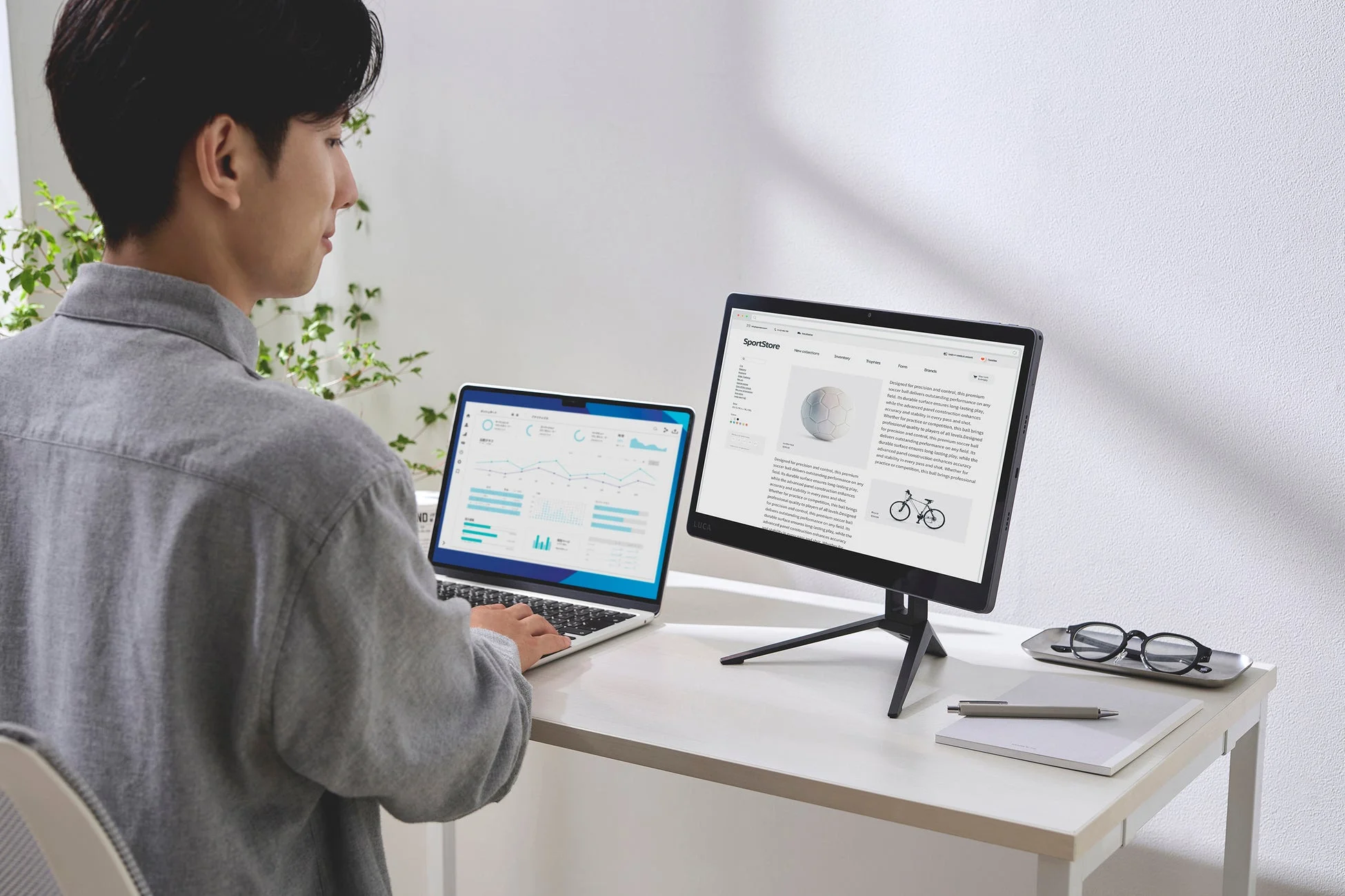 デスクでタブレットとPCを使う男性