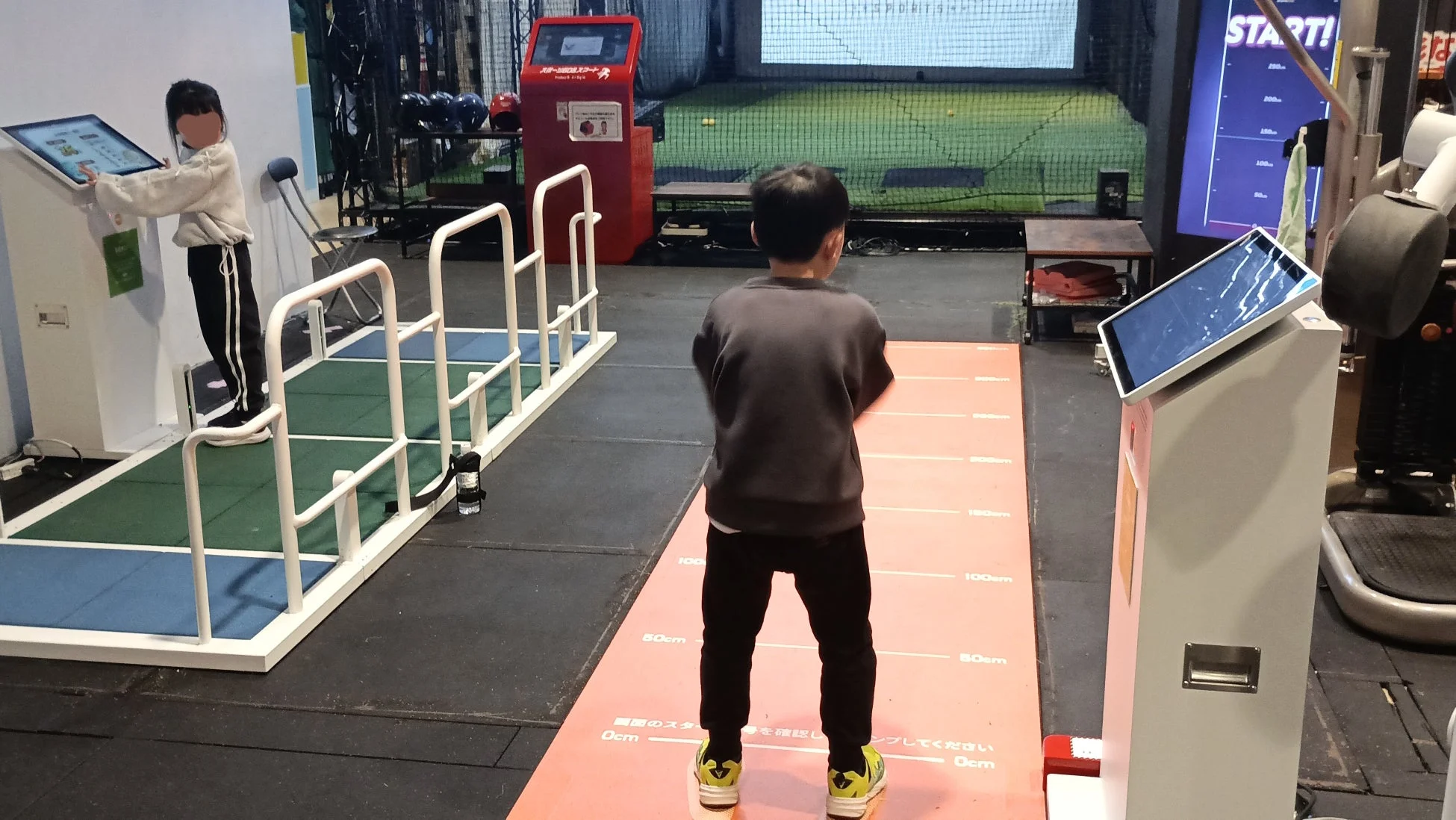 室内アミューズメント施設でスポーツ体験ゲームを楽しむ子供たち