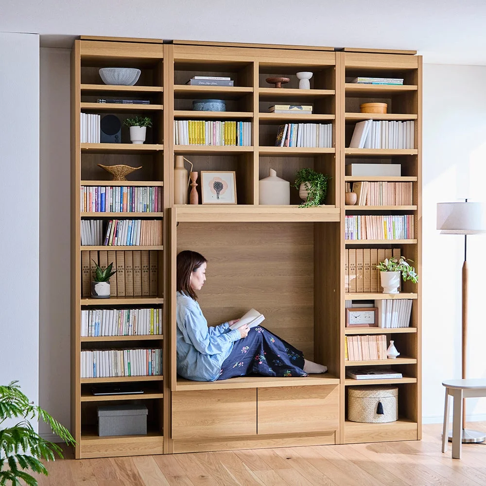 本棚のスペースで読書する女性