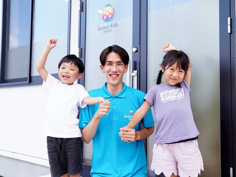 Global Kids methodの建物の前でポーズをとる教師と子供たち